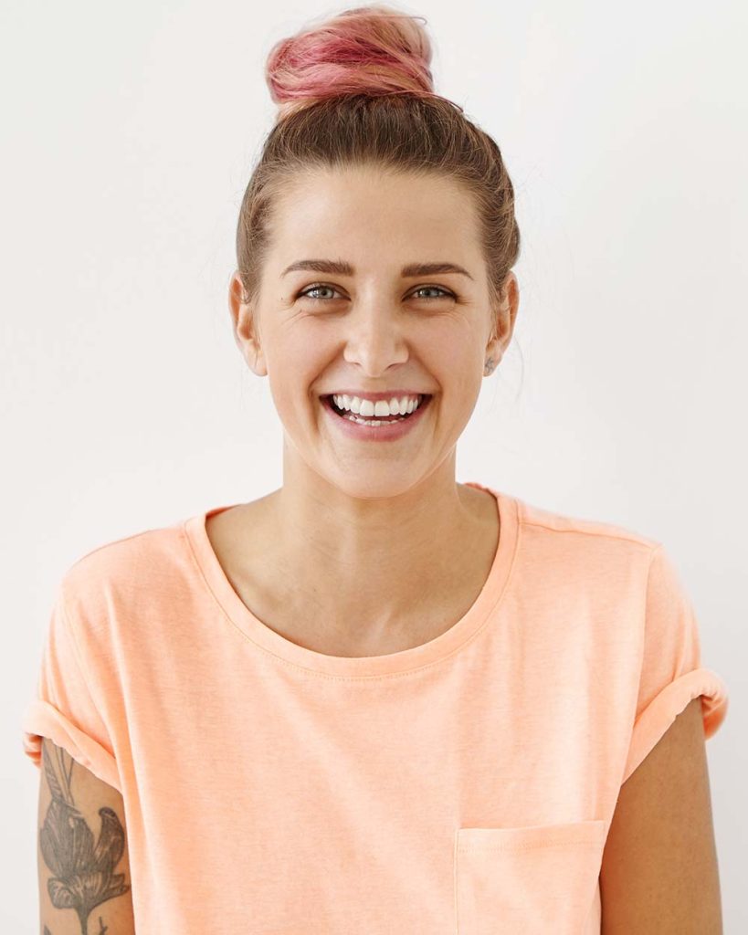 Donna con capelli rosa che sorride su sfondo bianco