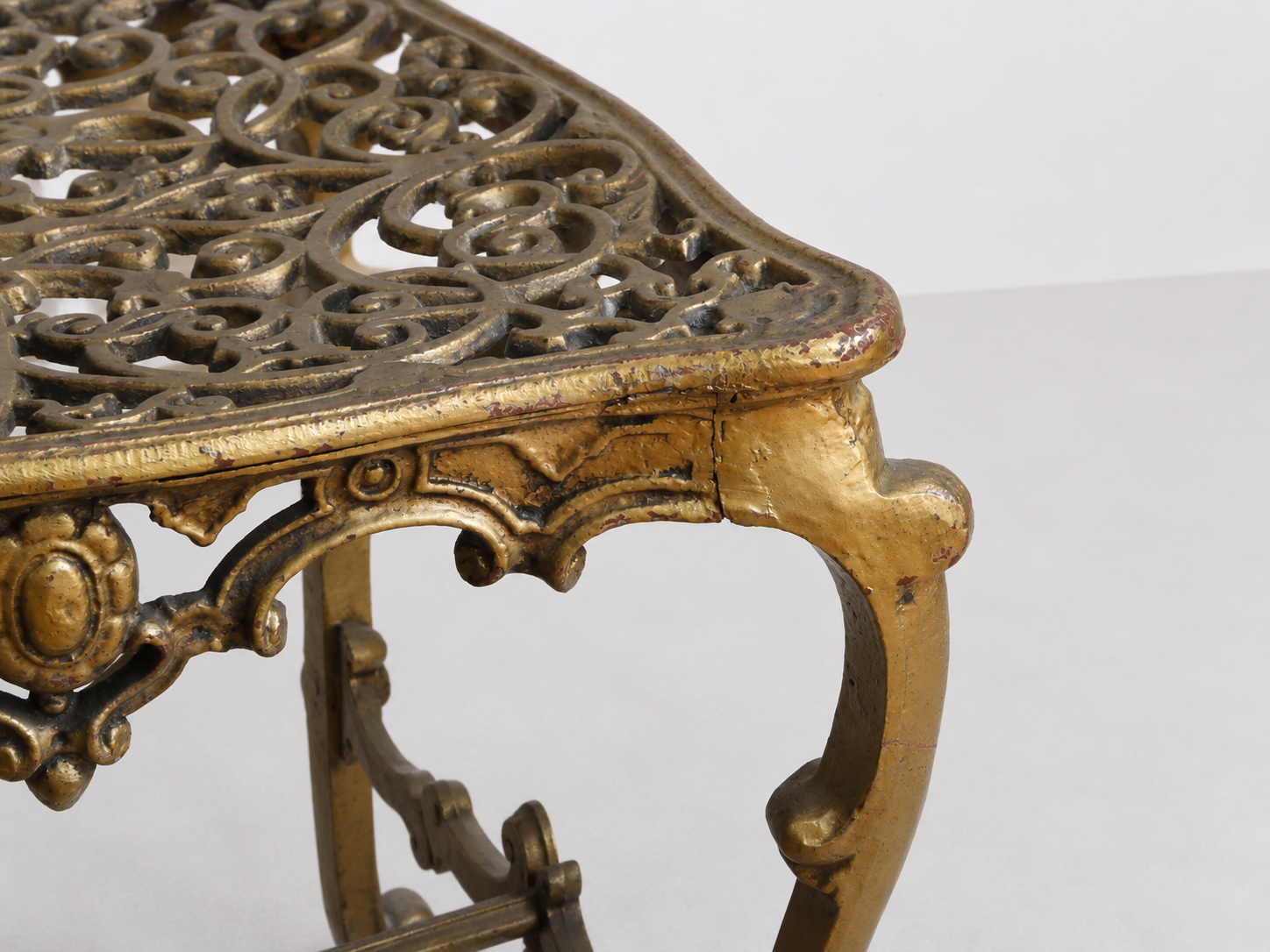 Dettaglio della seduta traforata e della gamba riccamente decorata di una sedia italiana in bronzo dorato stile Rococò.