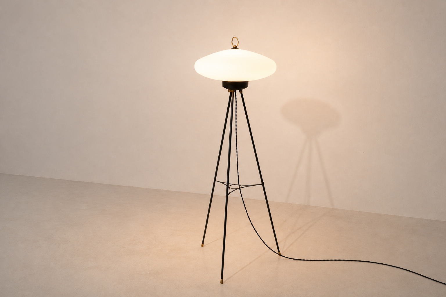Lampada da terra italiana Art Déco in ottone e vetro molato accesa, con diffusore a disco opalino e struttura a treppiede.