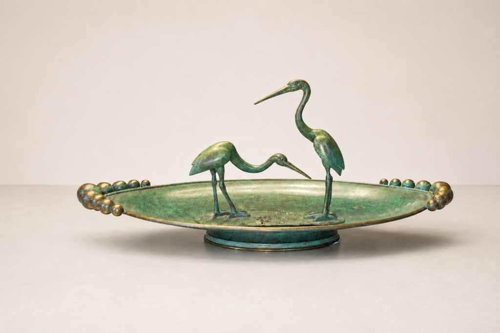 Centrotavola Art Déco in ottone patinato con due aironi scultorei e piatto decorativo.