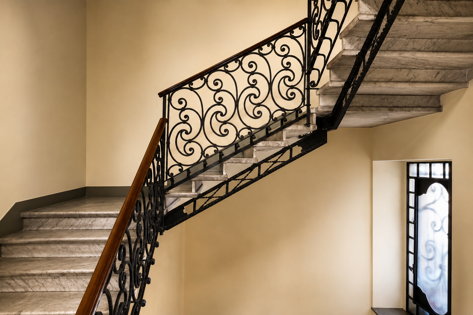 Scala Liberty con gradini in marmo e ringhiera in ferro battuto decorata a motivi floreali.